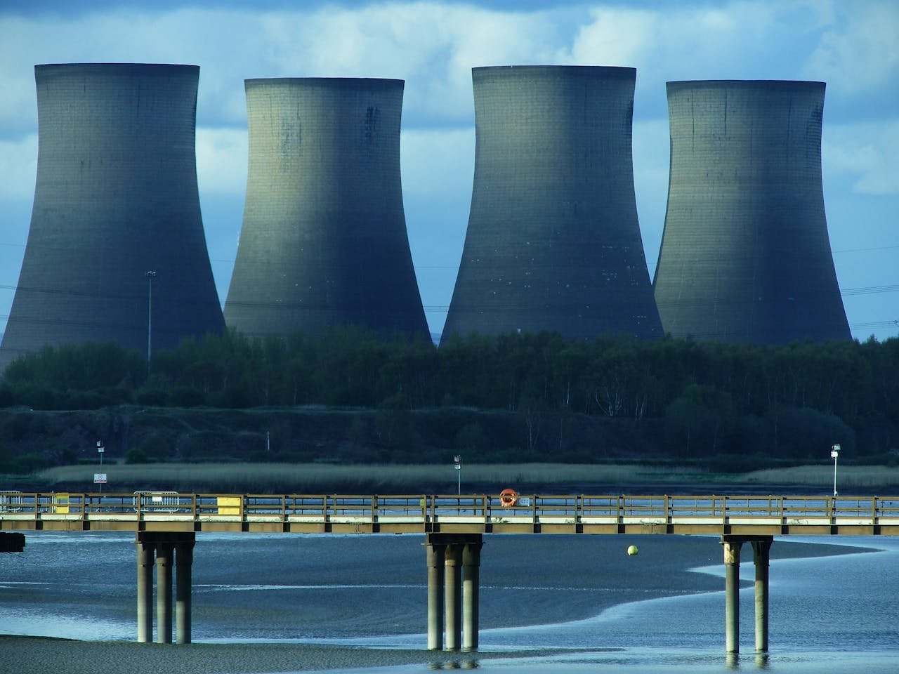 about-002 View of industrial cooling towers and a bridge over water, showcasing energy infrastructure.