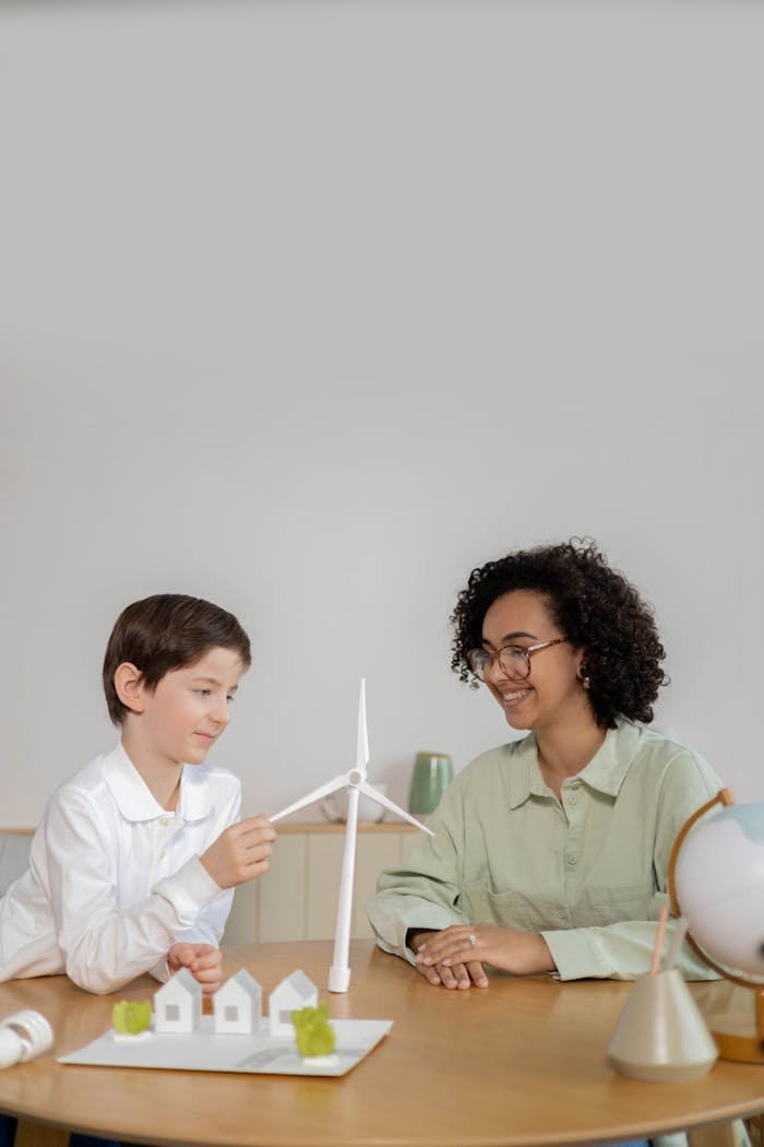 about-04 Child and teacher exploring wind energy with turbine model in classroom.